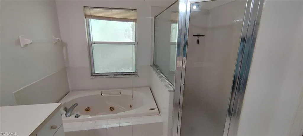 Bathroom featuring vanity and separate shower and tub