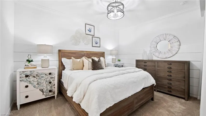 Carpeted bedroom featuring crown molding and an inviting chandelier
