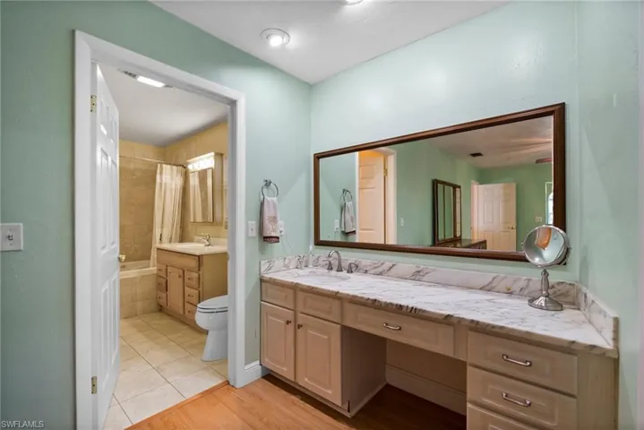 Full bathroom with vanity, shower / tub combo with curtain, toilet, and hardwood / wood-style floors