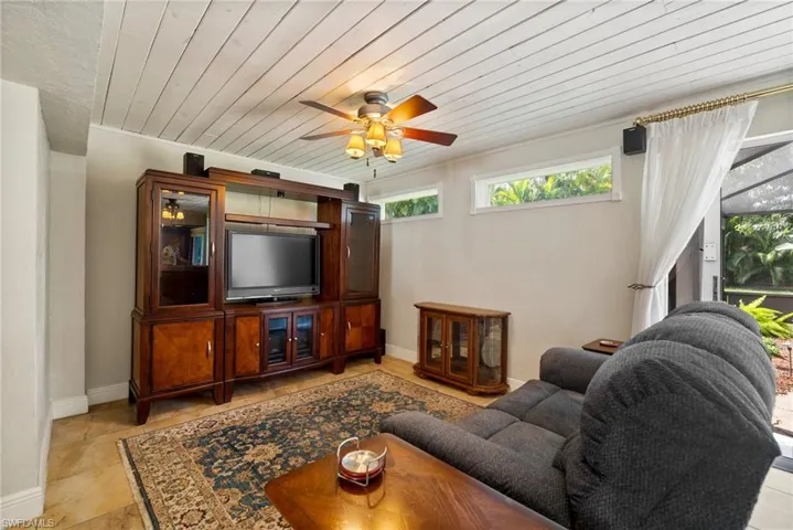 Living room featuring ceiling fan, light tile patterned flooring, and wooden ceiling