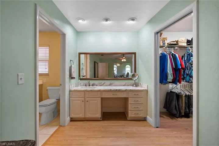 Bathroom with vanity, ceiling fan, wood-type flooring, and toilet