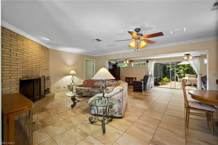 Tiled living room with ornamental molding, a fireplace, and ceiling fan