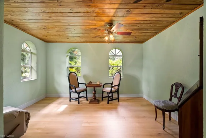 Living area with wooden ceiling, hardwood / wood-style flooring, plenty of natural light, and ceiling fan