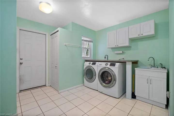 Laundry area featuring cabinets, light tile patterned floors, washer and dryer, and sink