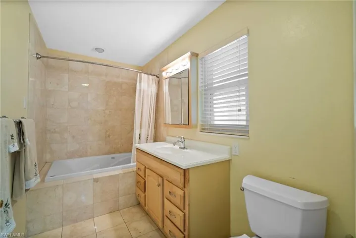 Full bathroom with tile patterned floors, vanity, shower / tub combo, and toilet