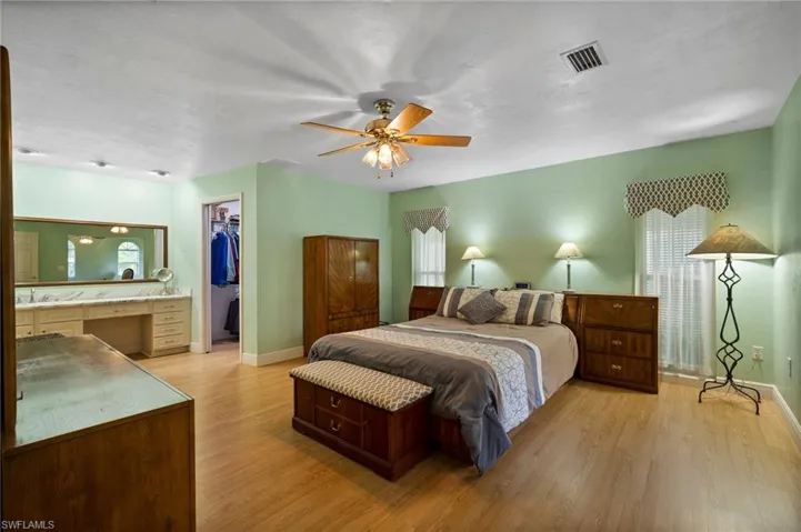 Bedroom with light wood-type flooring, a walk in closet, ceiling fan, and a closet