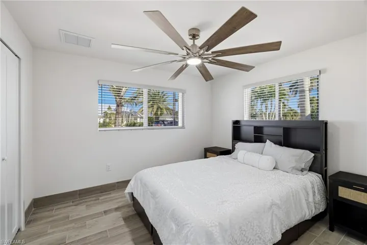 Bedroom with wood tiled floors, multiple windows, and ceiling fan