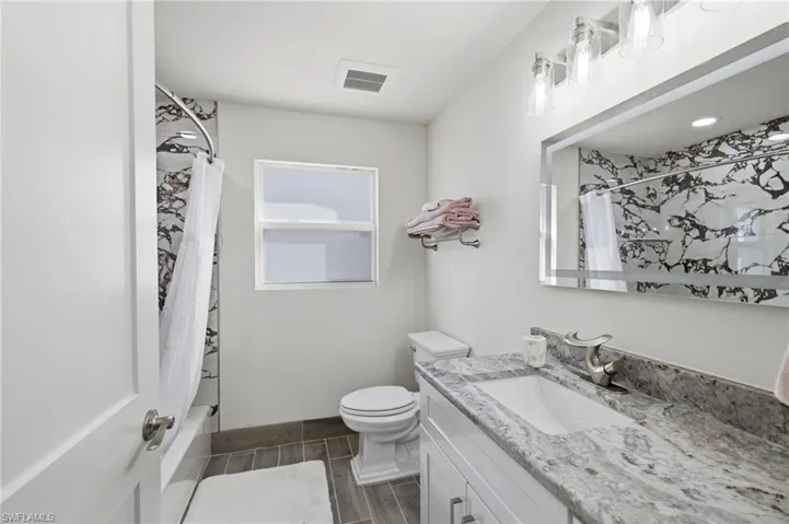 Full bathroom with vanity, shower / tub combo, and wood tiled floors