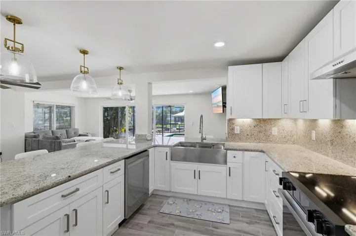 Kitchen featuring light stone countertops, black range with electric cooktop, white cabinetry, and recessed lighting