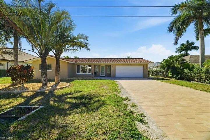 Ranch-style home with stucco siding, decorative driveway, an attached garage, a front yard, and a tile roof