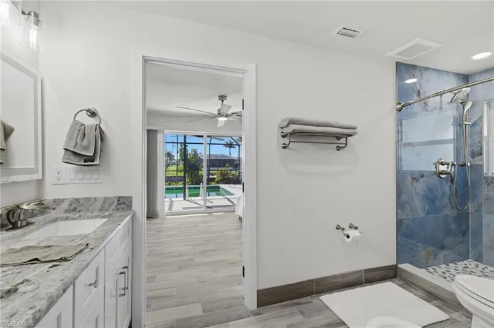 Full bath featuring a shower stall, vanity, wood tiled floors, and a ceiling fan