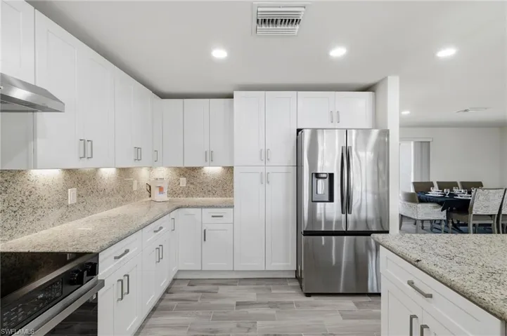 Kitchen featuring appliances with stainless steel finishes, light stone counters, recessed lighting, white cabinetry, and wood finish floors