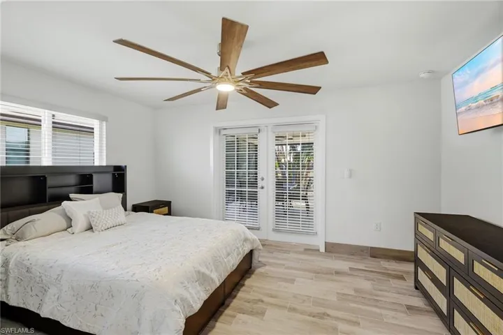 Bedroom with light wood-style floors, multiple windows, and access to outside