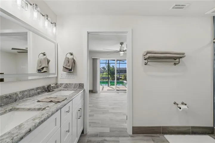 Bathroom featuring a ceiling fan, double vanity, and wood finish floors