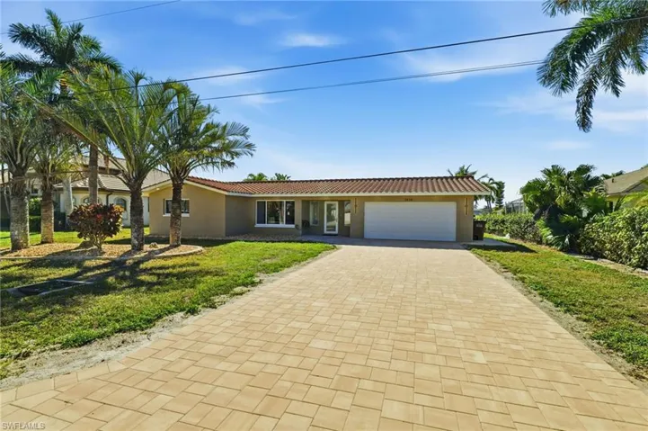 Ranch-style home featuring decorative driveway, a front lawn, stucco siding, an attached garage, and a tile roof
