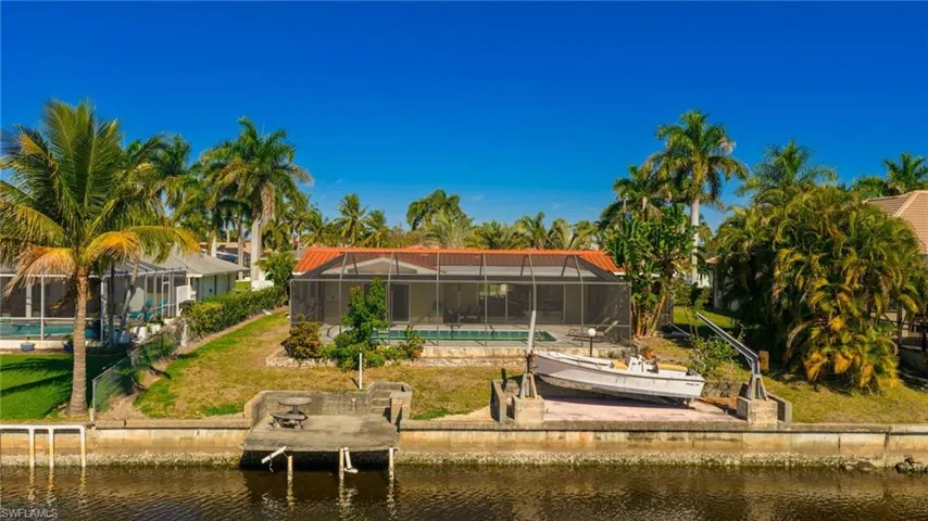 Back of property with a water view, a sunroom, glass enclosure, and a yard
