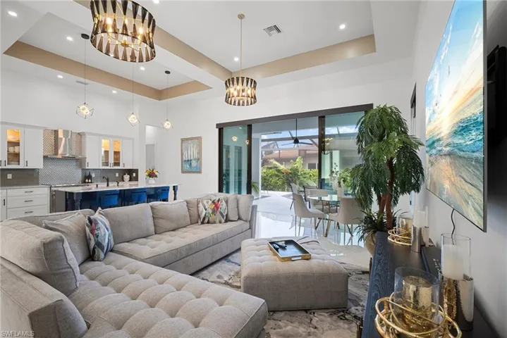 Living room with a notable chandelier, sink, and a tray ceiling