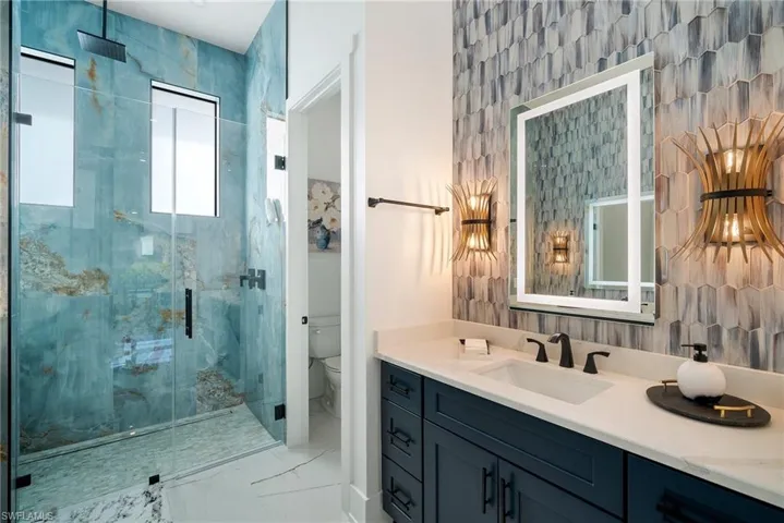 Bathroom featuring vanity, toilet, and a shower with door