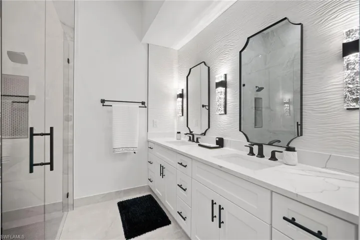 Bathroom with a shower with door, vanity, and tile patterned flooring