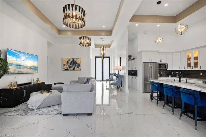 Living room with a tray ceiling, a towering ceiling, and a notable chandelier