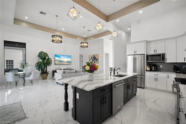 Kitchen with a tray ceiling, white cabinets, pendant lighting, and appliances with stainless steel finishes