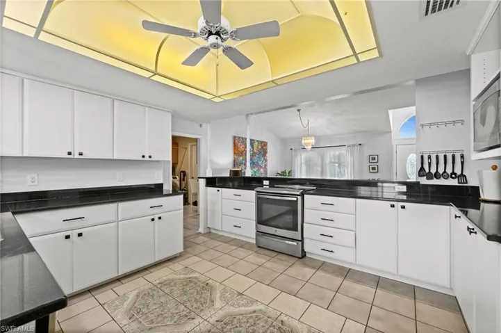 Kitchen featuring stainless steel appliances, white cabinetry, and dark stone counters