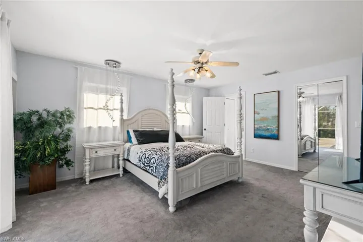 Bedroom with carpet, ceiling fan, and multiple windows