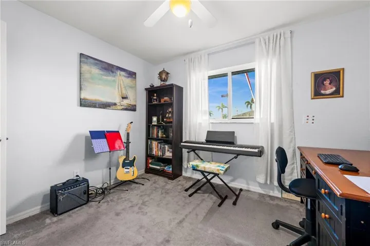 Home office with light colored carpet and ceiling fan