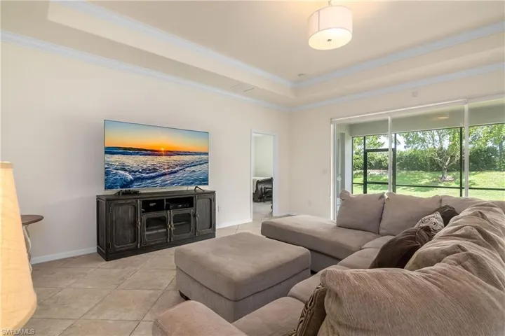 Tiled living room featuring ornamental molding and a tray ceiling