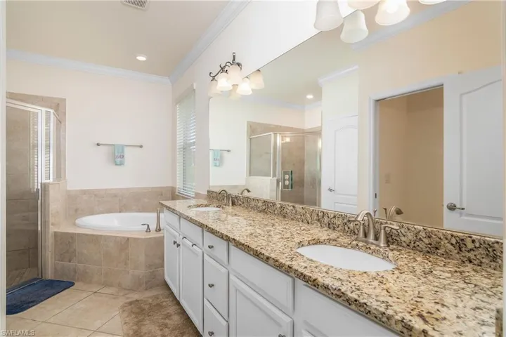 Bathroom featuring tile flooring, crown molding, independent shower and bath, double sink, and large vanity