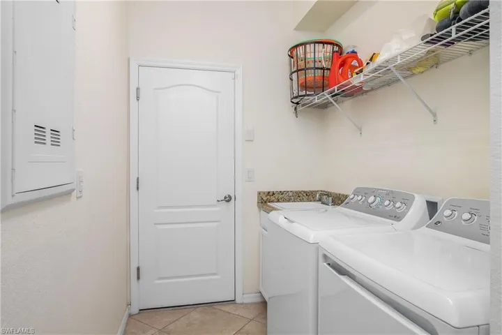Laundry room with washer and dryer, sink, and light tile flooring
