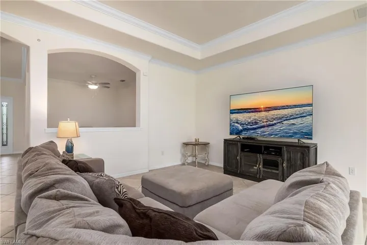 Tiled living room with ceiling fan and crown molding