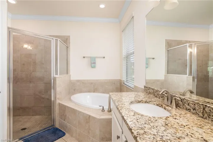 Bathroom featuring tile floors, ornamental molding, separate shower and tub, and large vanity