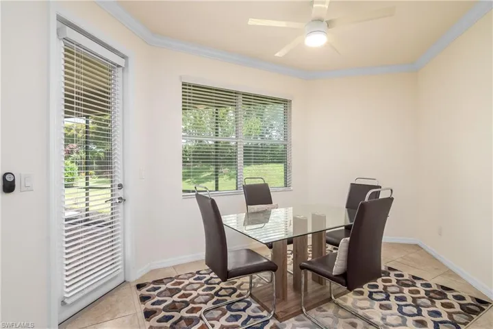 Tiled dining area featuring ceiling fan and crown molding