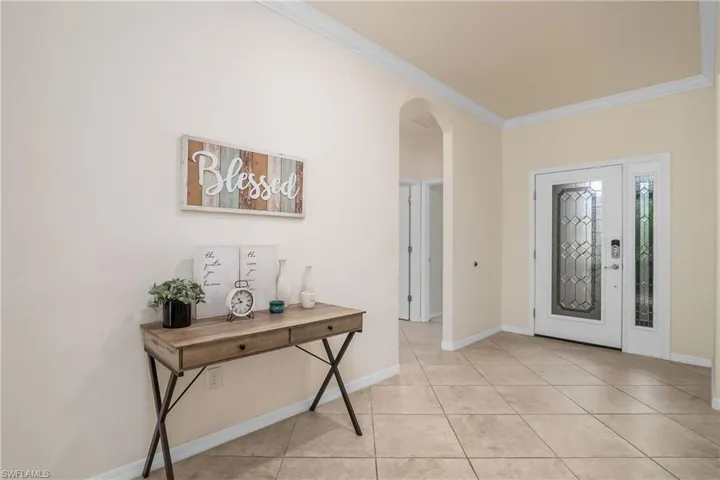 Tiled foyer featuring crown molding
