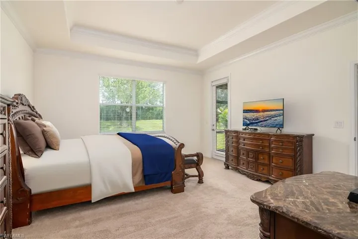 Carpeted bedroom with a raised ceiling and ornamental molding