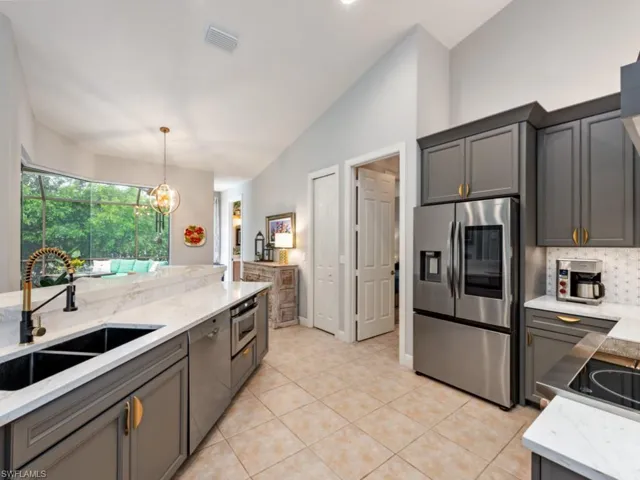 Kitchen with stainless steel appliances, vaulted ceiling, sink, pendant lighting, and light tile patterned floors
