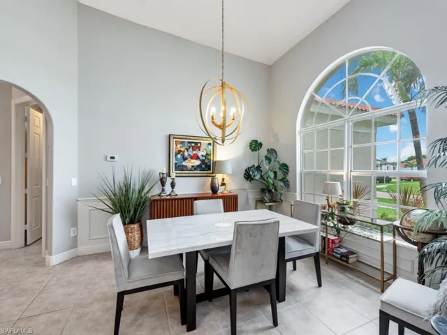 Dining area featuring lofted ceiling, light tile patterned floors, and a chandelier