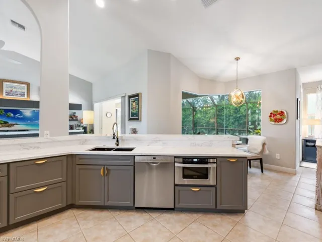 Kitchen with gray cabinets, lofted ceiling, appliances with stainless steel finishes, and sink