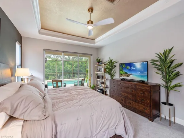 Carpeted bedroom with ceiling fan, a textured ceiling, and a tray ceiling