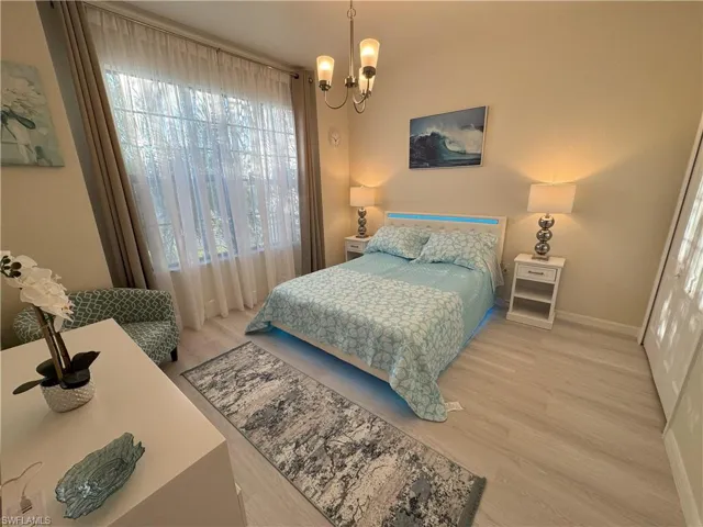 Bedroom with light wood-style floors and hanging lights