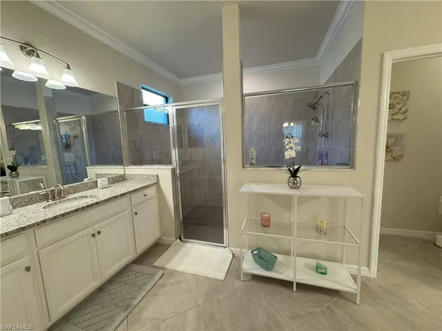 Full bathroom featuring crown molding, a shower stall, vanity, and light tile patterned floors