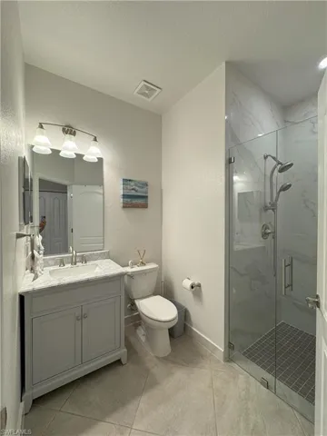 Full bath featuring a textured wall, vanity, a marble finish shower, and a textured ceiling