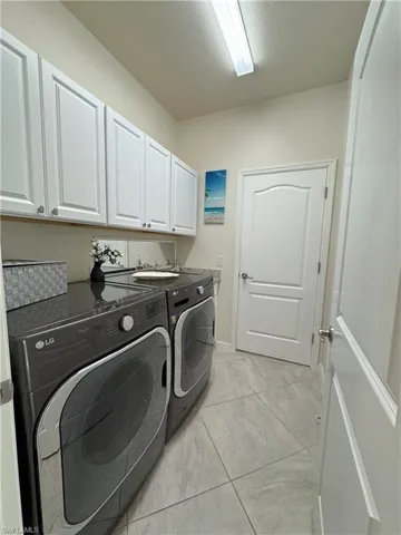 Laundry area featuring washing machine and clothes dryer, cabinet space, and a textured ceiling