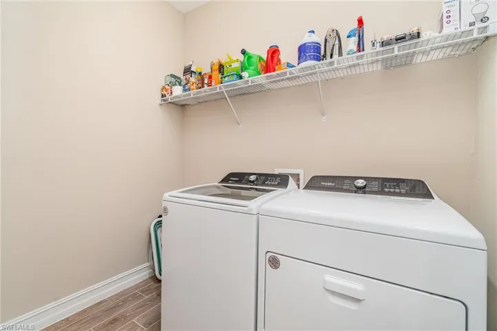 Washroom with hardwood / wood-style flooring and washing machine and dryer