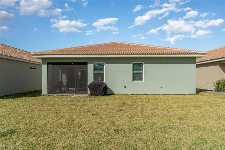 Rear view of house with a sunroom and a lawn
