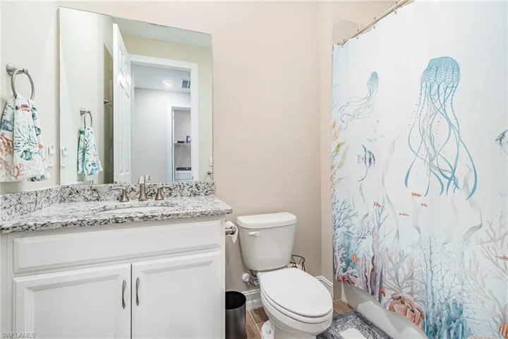 Full bathroom featuring vanity, shower / bath combo with shower curtain, toilet, and hardwood / wood-style flooring