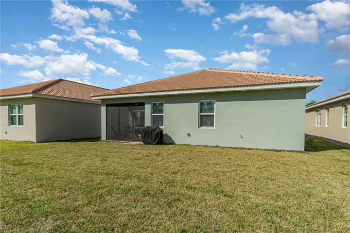 Back of property with a lawn and a sunroom