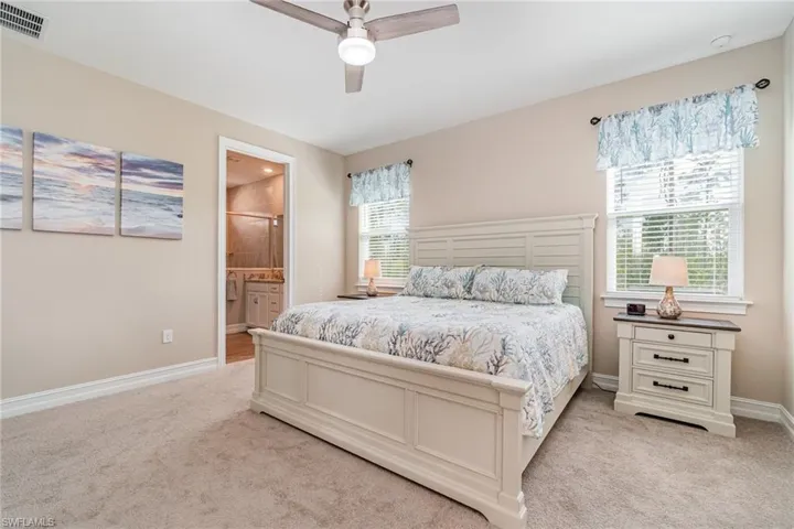 Carpeted bedroom featuring connected bathroom and ceiling fan