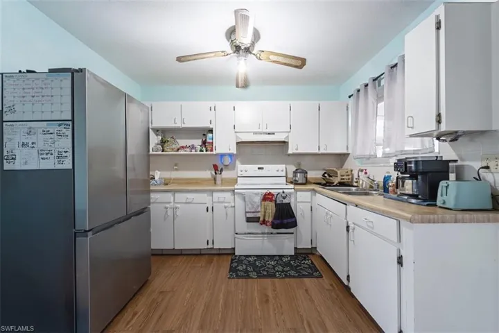 Kitchen featuring freestanding refrigerator, electric stove, light countertops, and white cabinetry